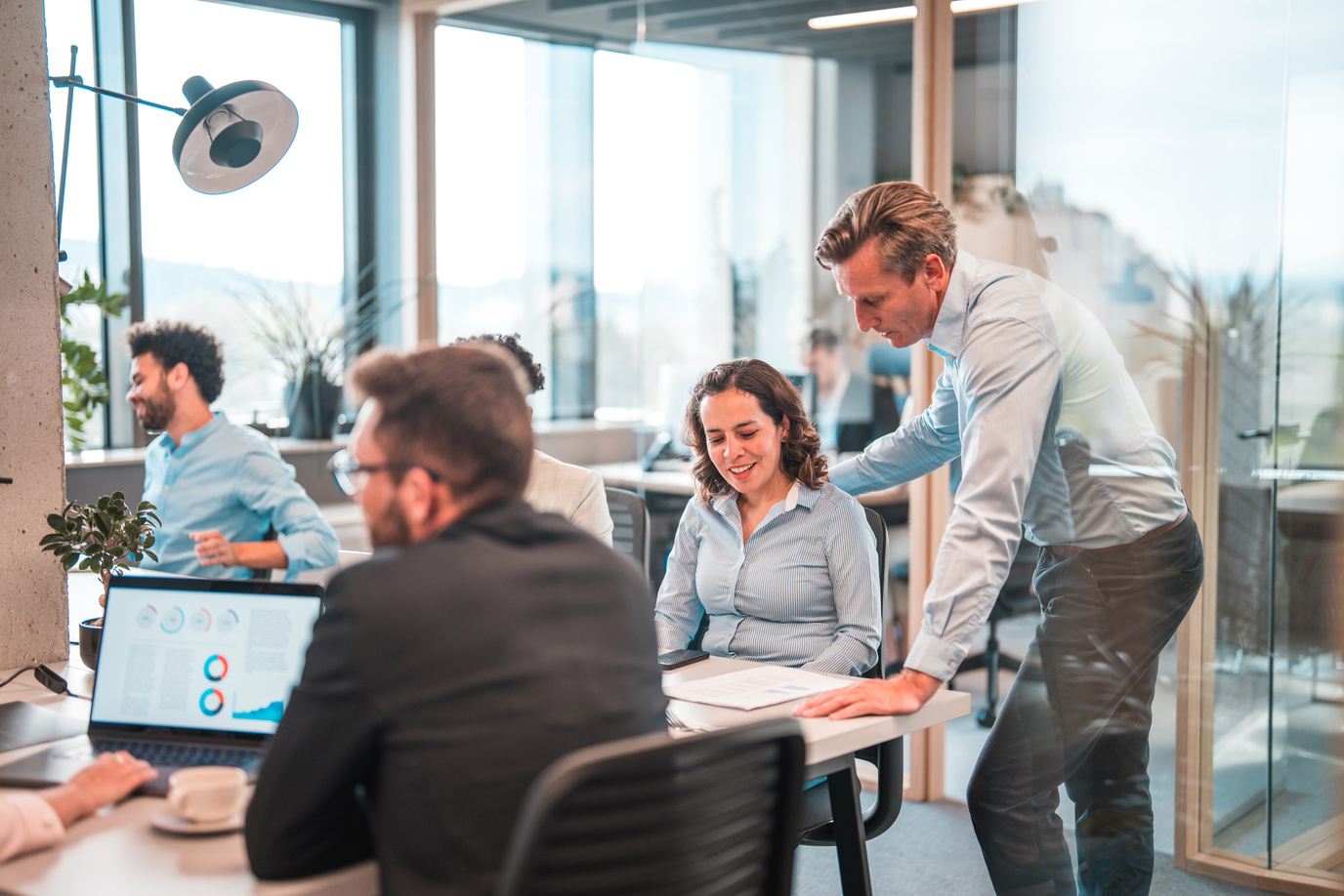 Mature Male Manager Helping A Hispanic Female Intern In A Marketing Agency